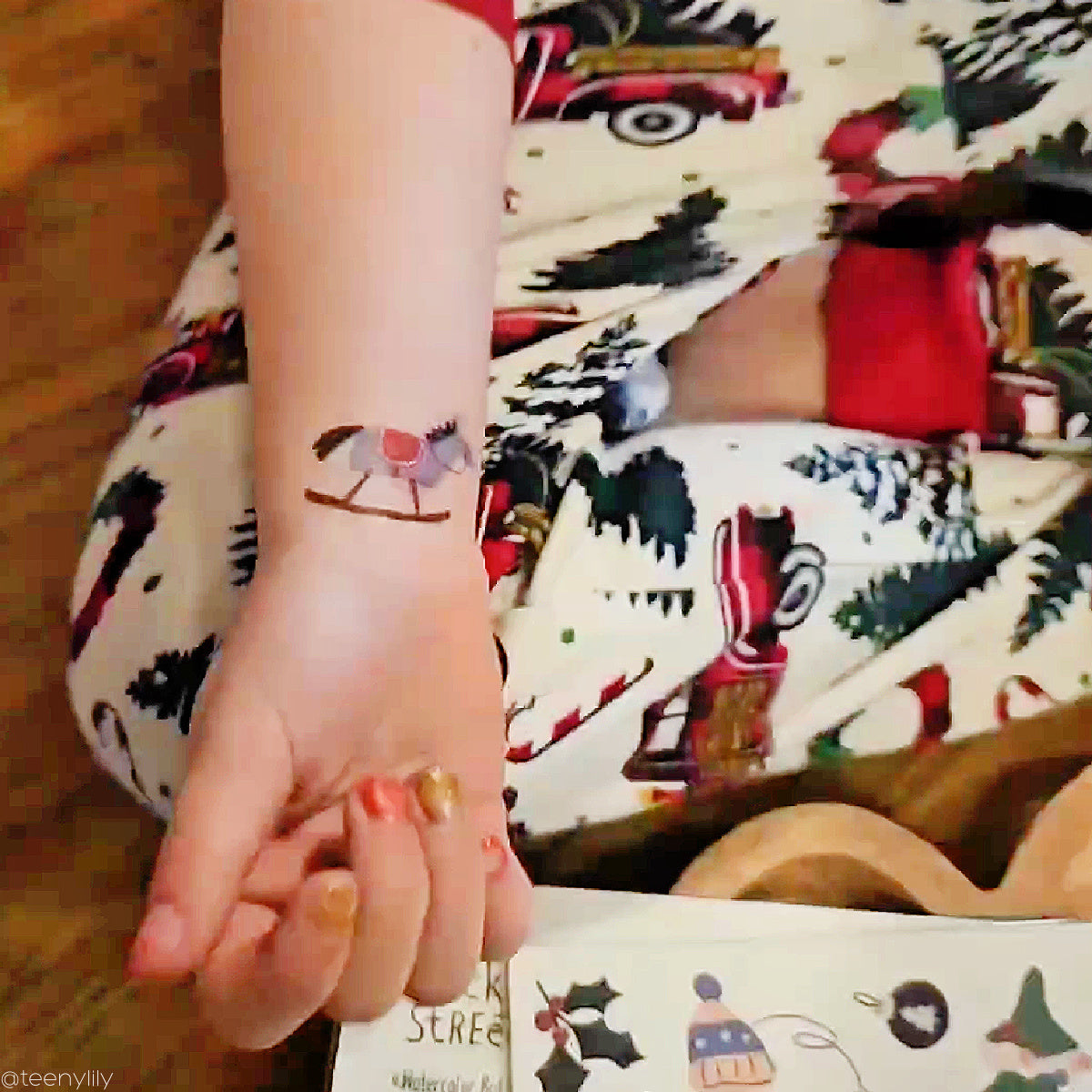 Hand with a small temporary tattoo of a horse and rider, wearing a patterned outfit.