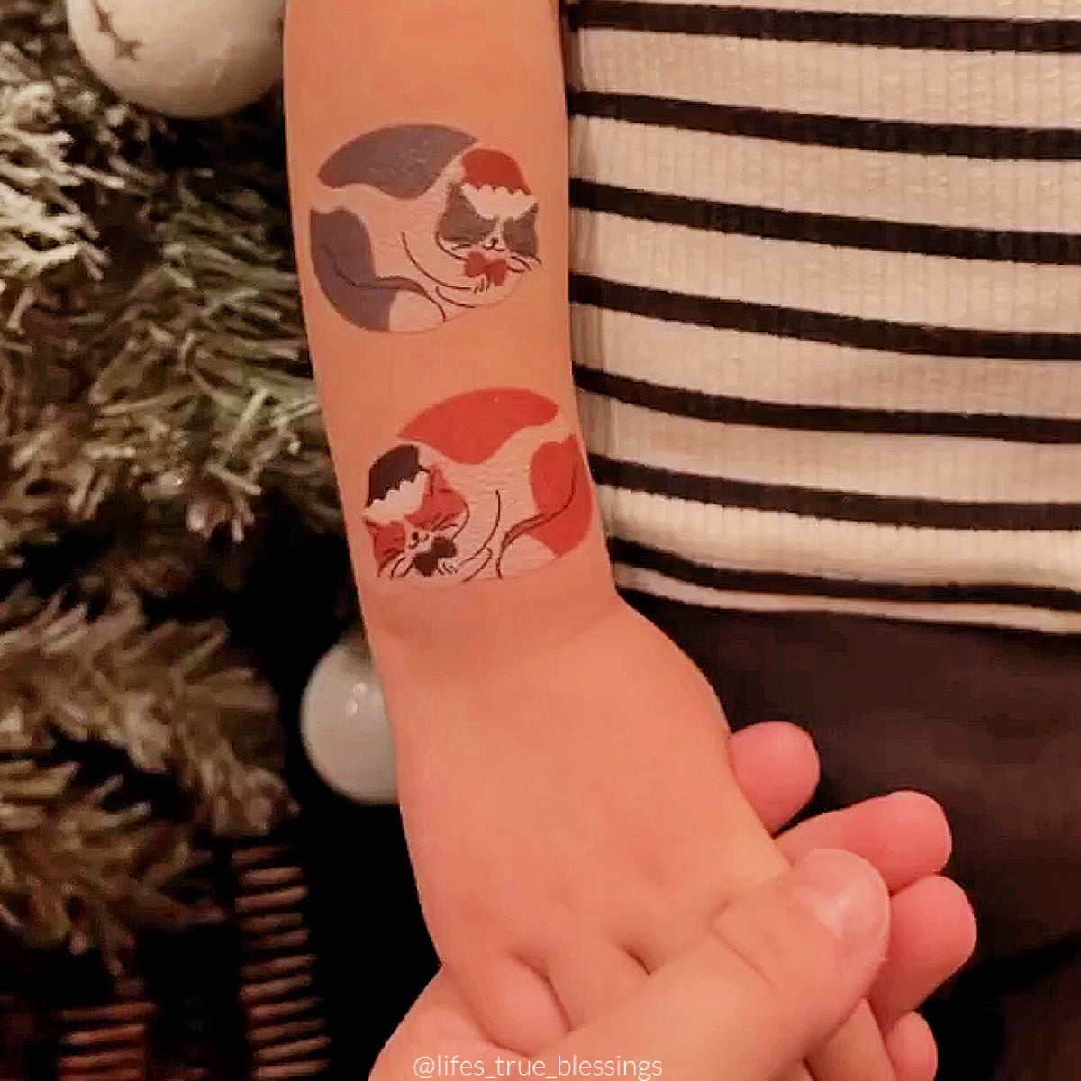 Temporary tattoo of cats with Christmas hats on a child's arm.