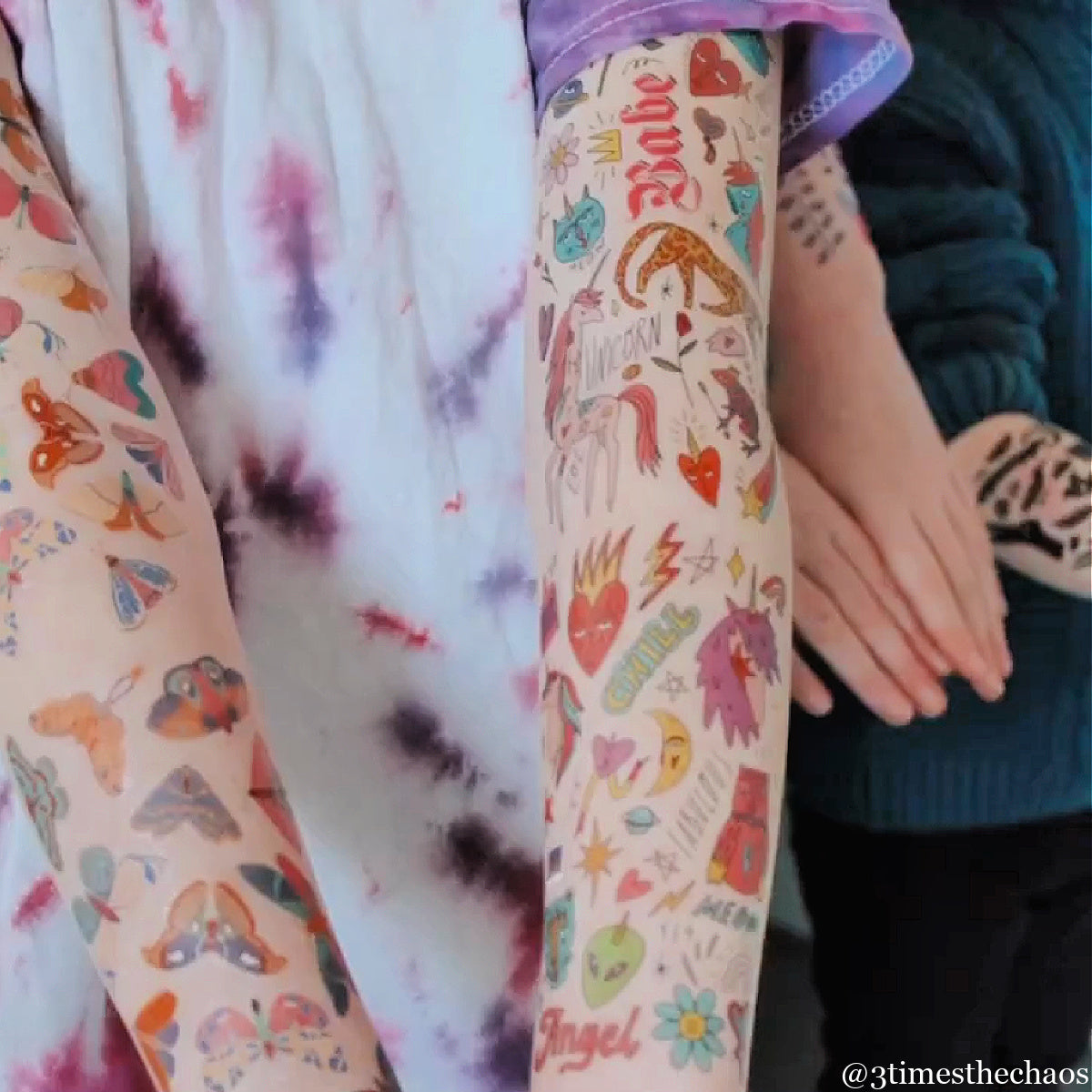 Temporary tattoo sleeves with colorful patterns and text worn by a child.