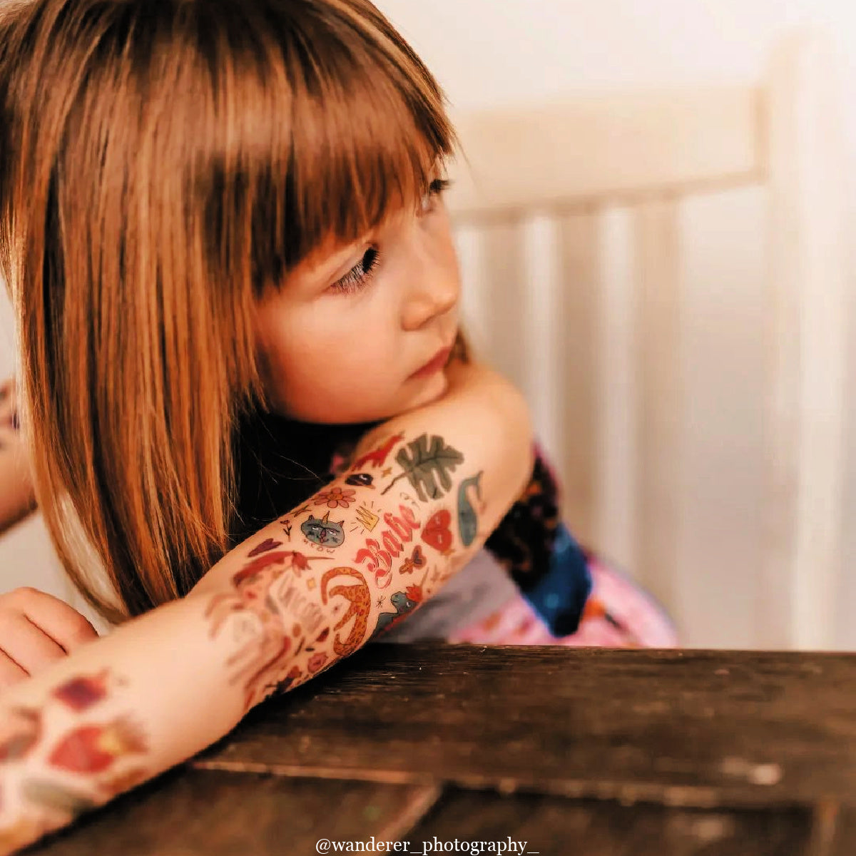 Child with floral tattoos on arm sitting at a table