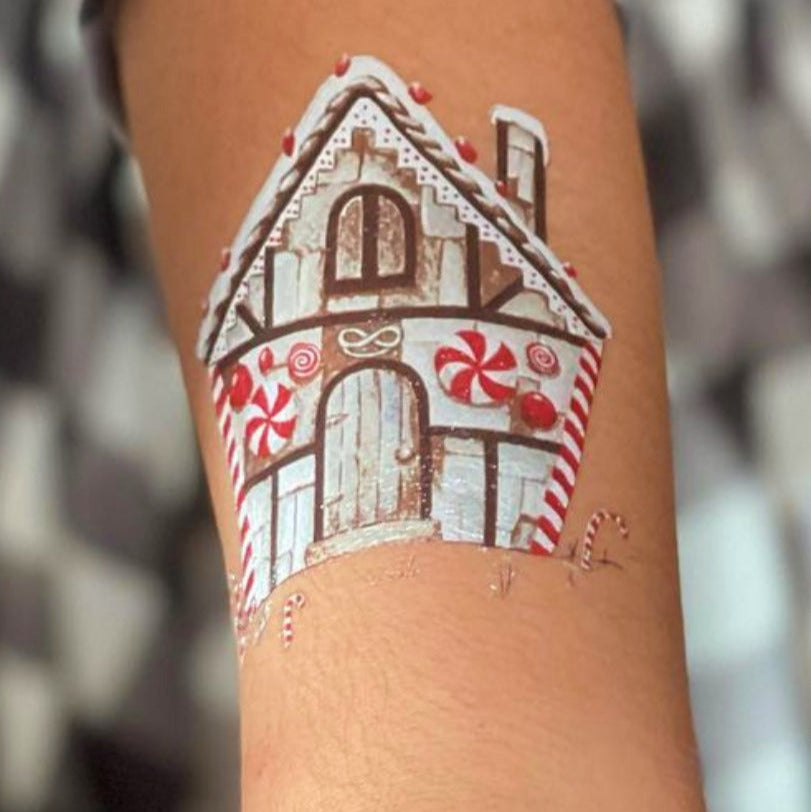 Temporary tattoo of a gingerbread house on a child's arm.