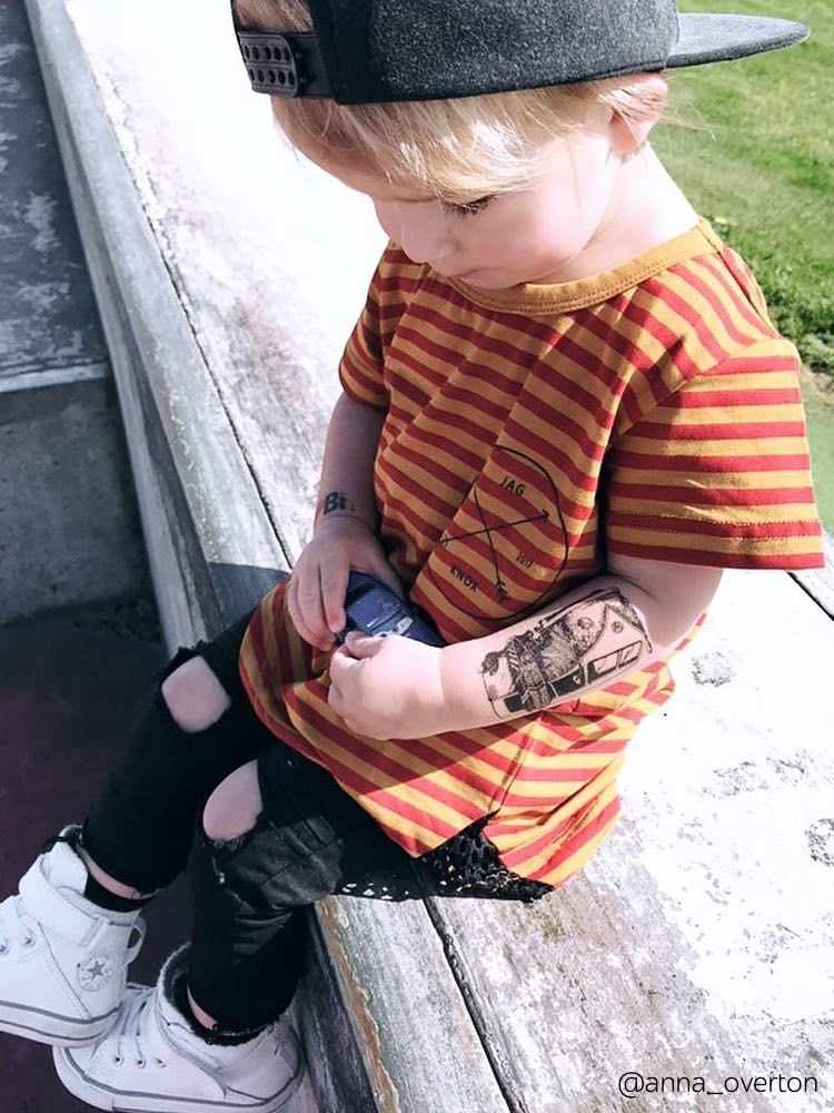 Little boy wearing temporary tattoo with legendary Volskwagen T1 hippie bus.
